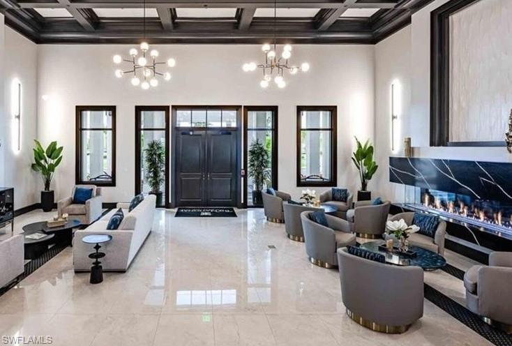 Spacious lobby featuring a coffered ceiling, polished tile flooring, and a linear fireplace with a marble surround