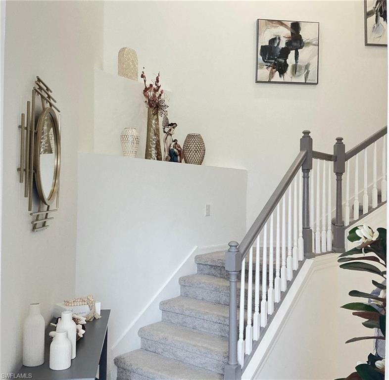 Staircase featuring carpeted treads, painted balusters, and a gray handrail