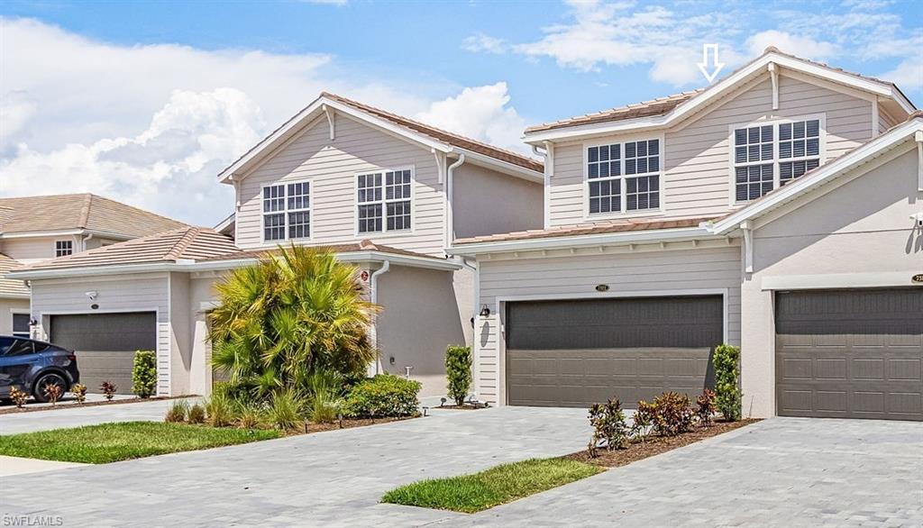 Contemporary two-story residence featuring light siding, a tiled roof, and an attached garage with a dark door