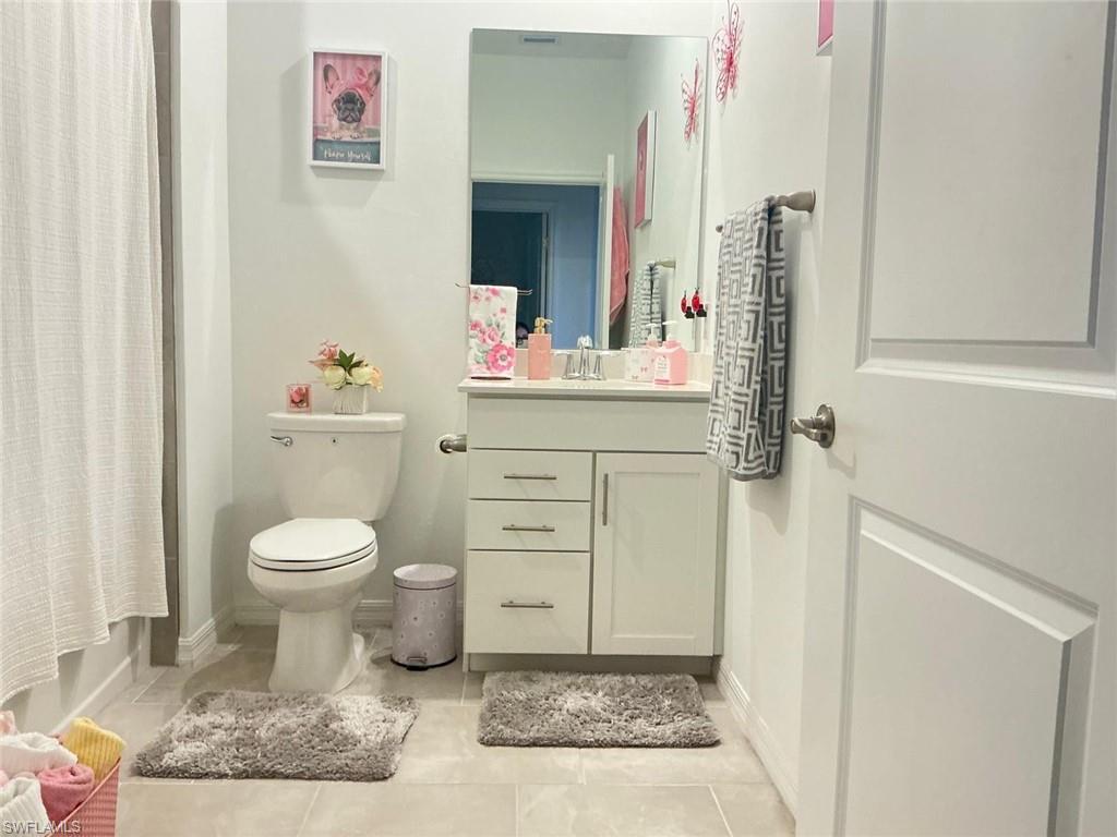 Bathroom featuring a white vanity with brushed nickel hardware, a rectangular vanity mirror, and a white toilet