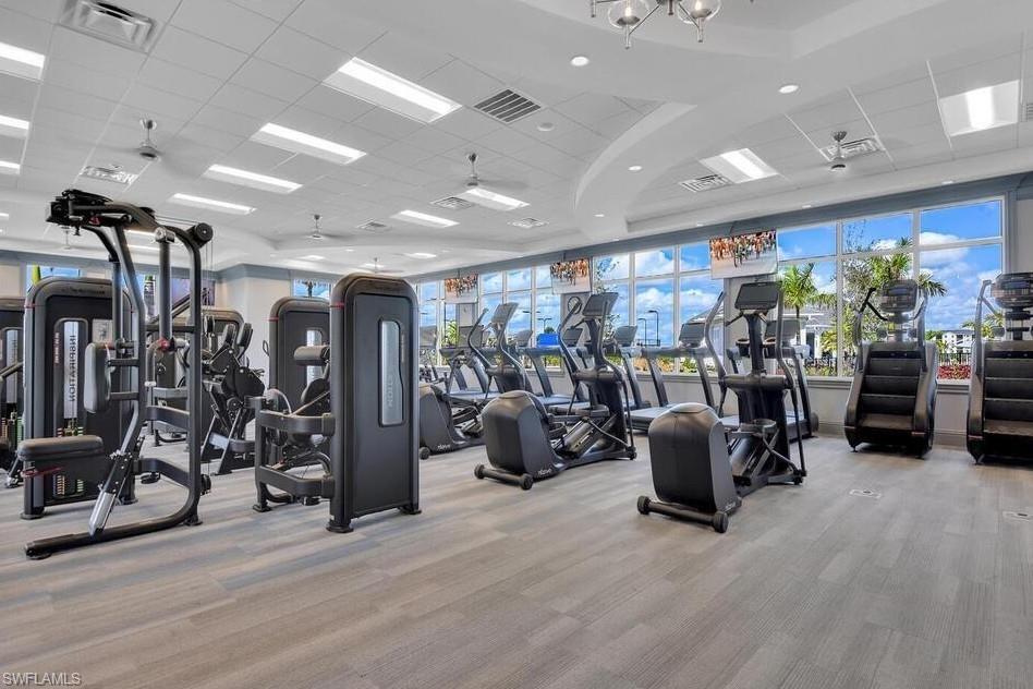 Modern fitness center featuring a comprehensive selection of exercise equipment, expansive window walls, recessed lighting, ceiling fans, and wood-finish flooring