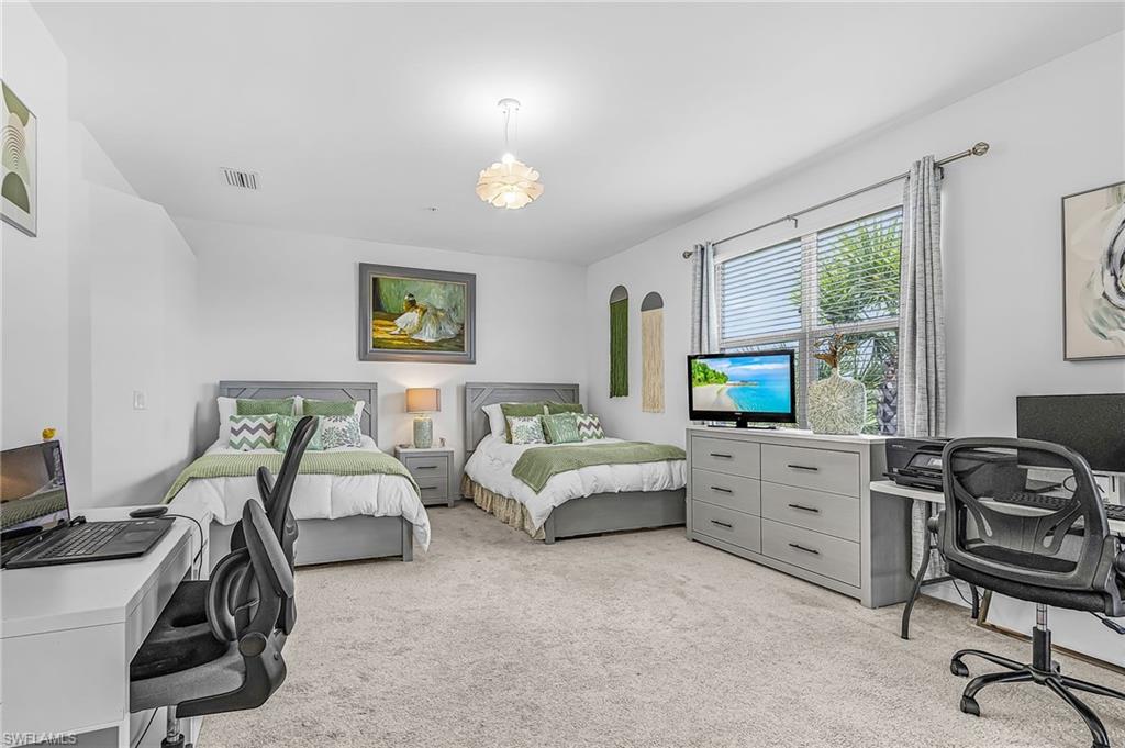 Carpeted room featuring two beds with gray headboards, white walls, and a window with blinds