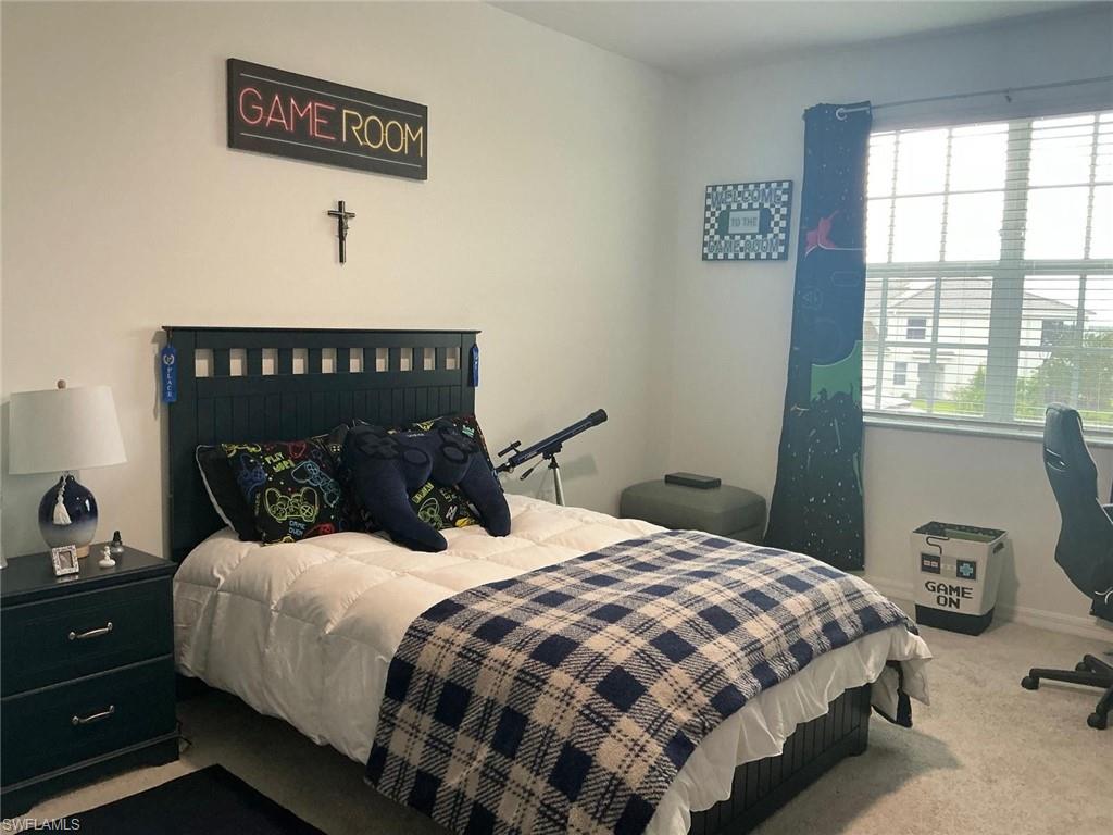Bedroom featuring a dark wood headboard, a window with horizontal blinds, and light-colored wall-to-wall carpeting