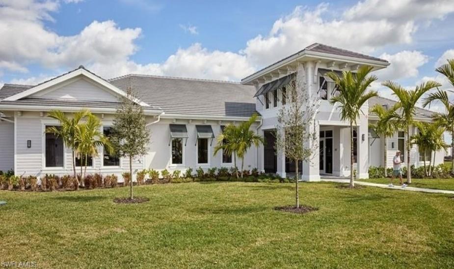 Contemporary architectural design featuring a prominent entry tower, crisp white exterior, dark shingle roof, decorative window awnings, and mature palm trees