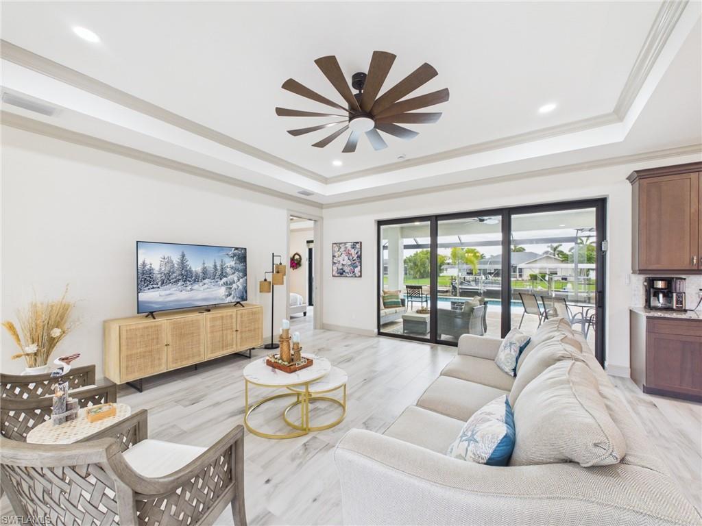Dining area featuring wood-finish flooring, a tiered ceiling, and a contemporary chandelier