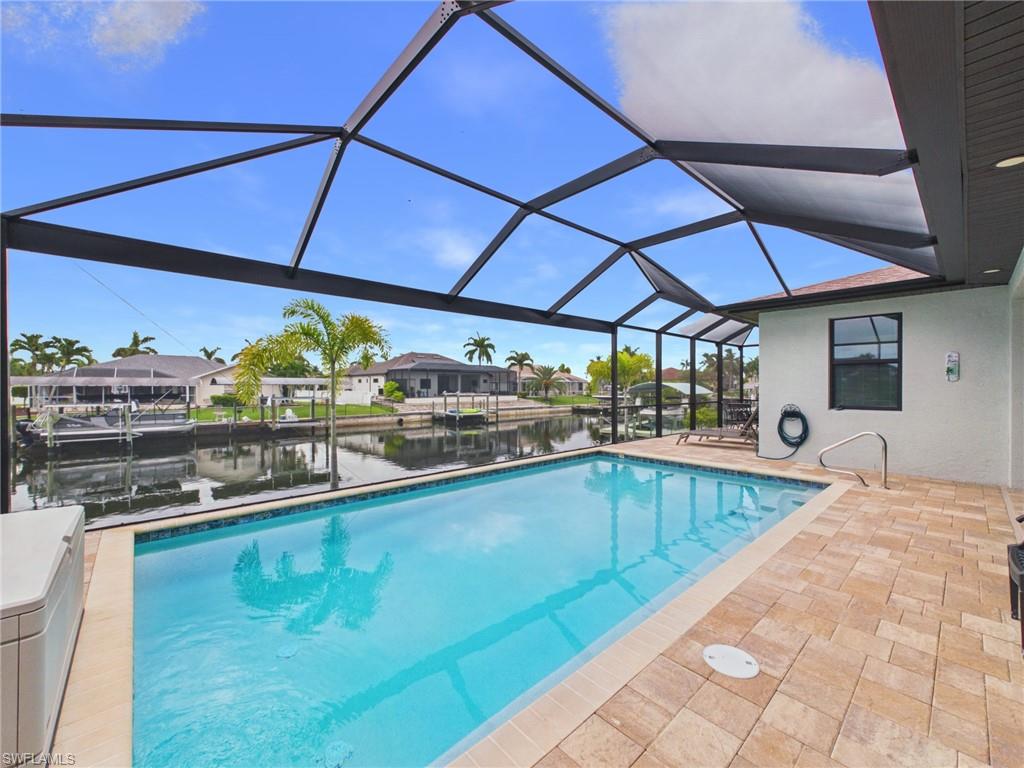 Screened outdoor living area featuring a rectangular pool with integrated steps, paver decking, and a covered patio with recessed lighting and a ceiling fan