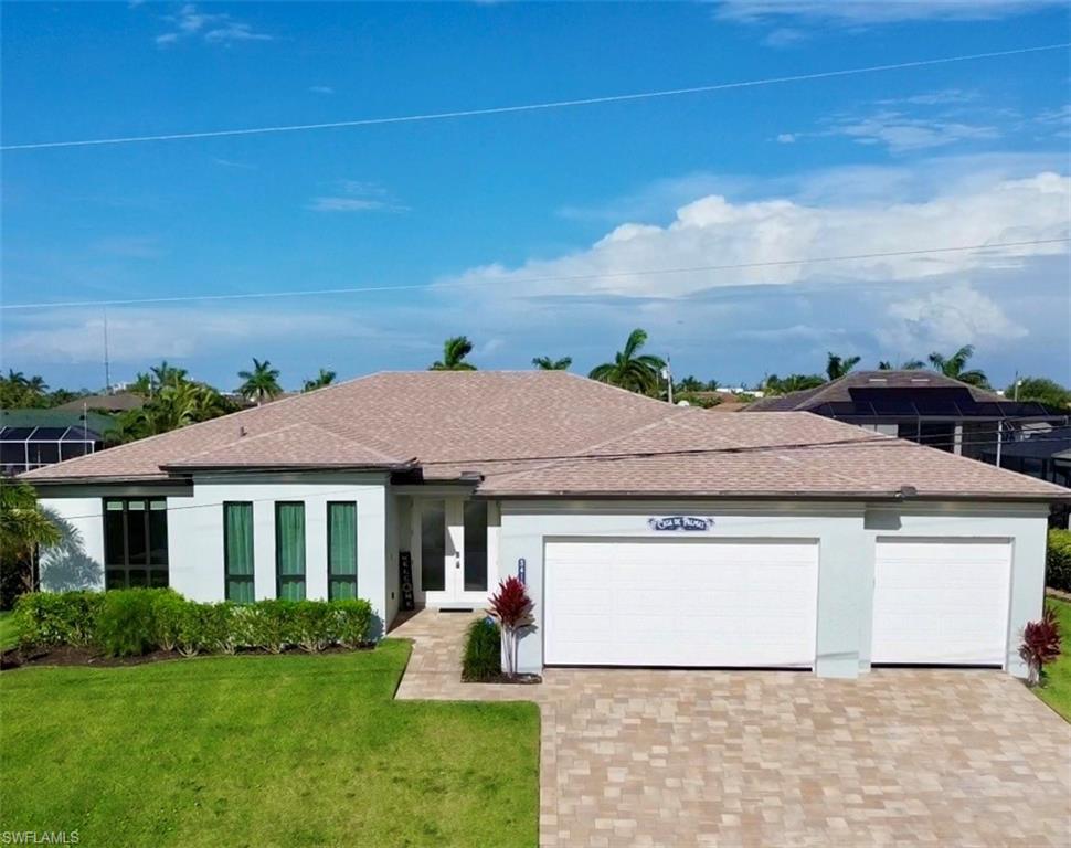 Contemporary-style residence featuring a paved driveway, two-car garage, manicured lawn, and mature landscaping
