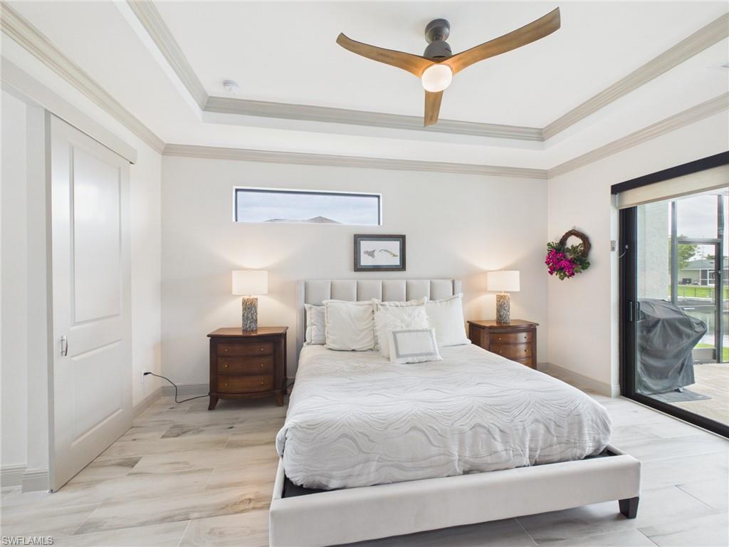 Bedroom featuring light-toned wood-finish flooring, a ceiling fan with integrated lighting, and a single window with curtain rods