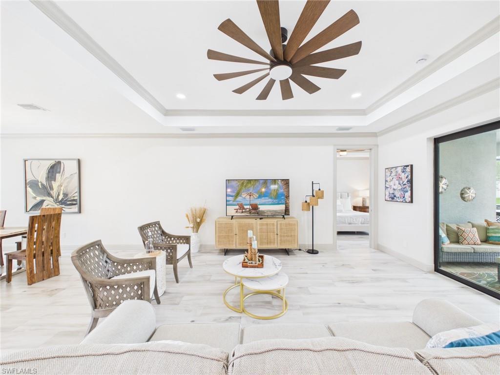 Bright dining area featuring light-toned wood-finish flooring, white walls with crown molding, and multiple tall windows