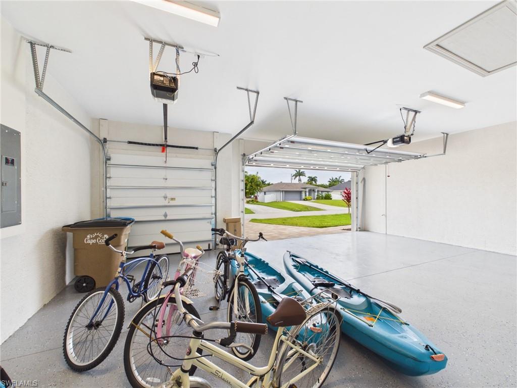 Exterior featuring a three-car garage, an expansive paver driveway, and a well-maintained lawn
