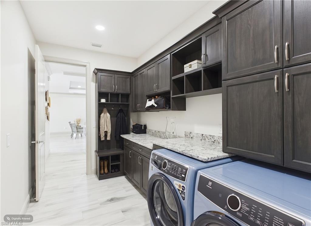 Spacious bath featuring dual vanities with integrated sinks, ample dark cabinetry, and a large window with roller shades