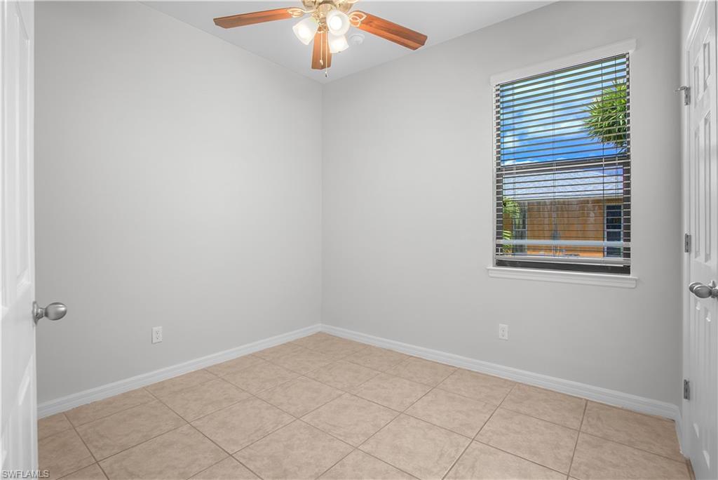 Room featuring neutral wall paint, tiled flooring, a window with horizontal blinds, and a ceiling fan with light fixture