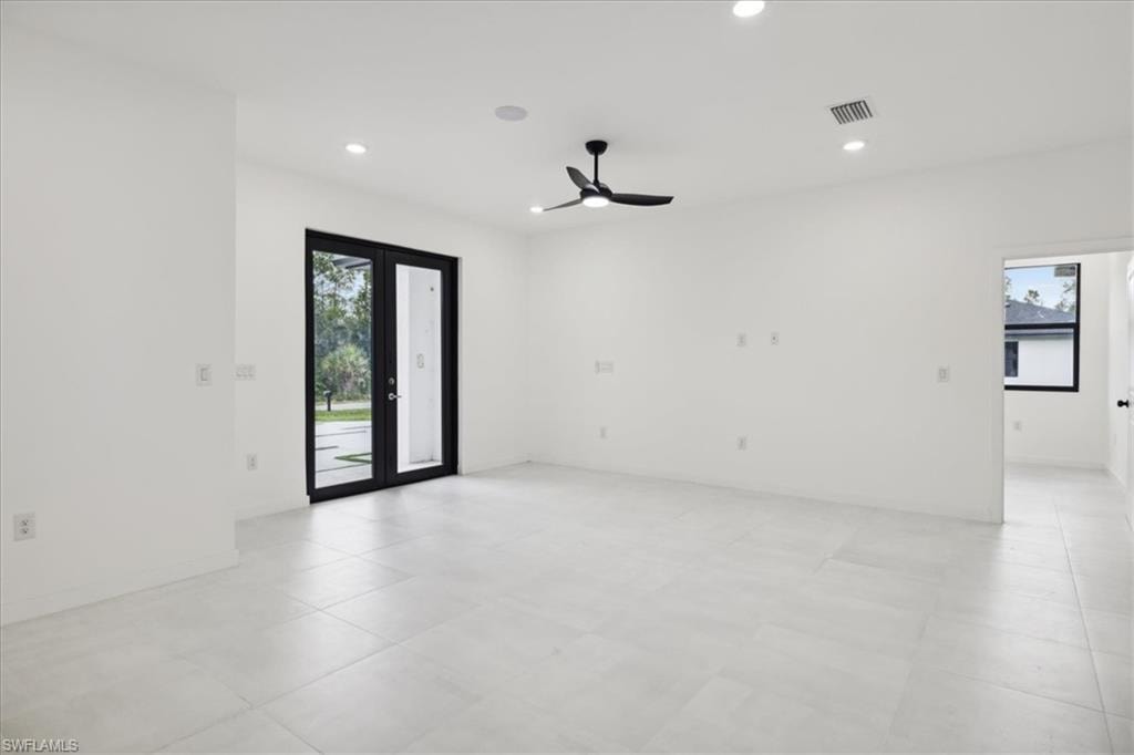Empty room featuring plenty of natural light, ceiling fan, and french doors