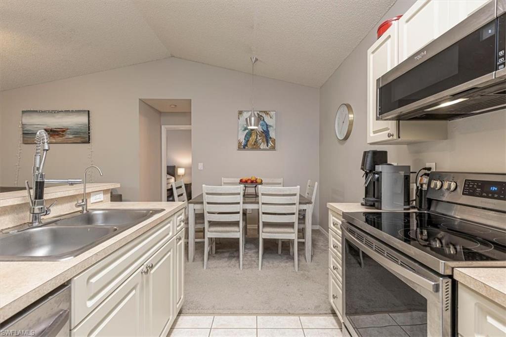 Kitchen with appliances with stainless steel finishes, light countertops, white cabinetry, a textured ceiling, and light tile patterned floors