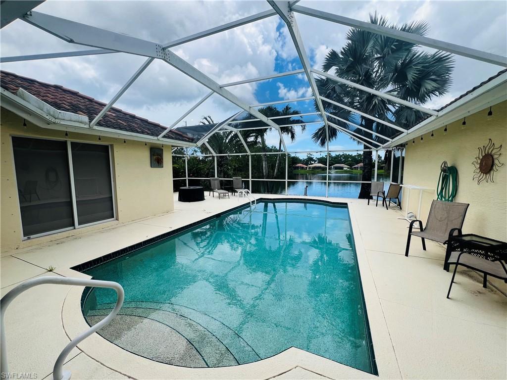 View of pool with a patio area and glass enclosure