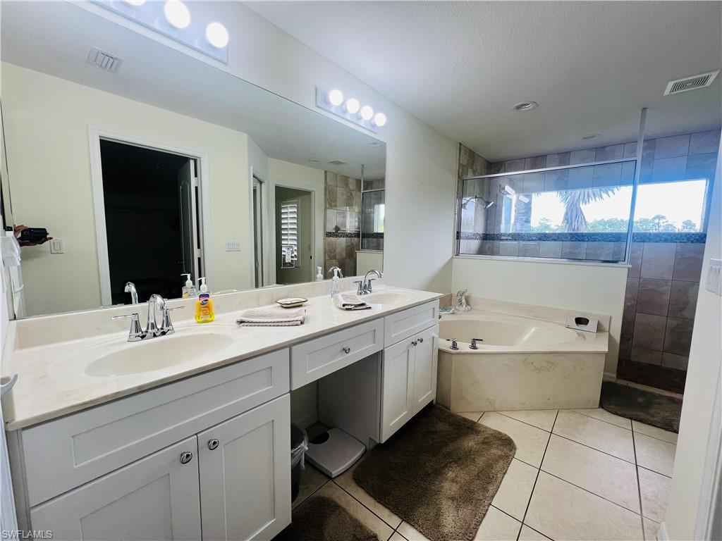 Master Bathroom with tile patterned floors, shower with separate bathtub, and double sink vanity