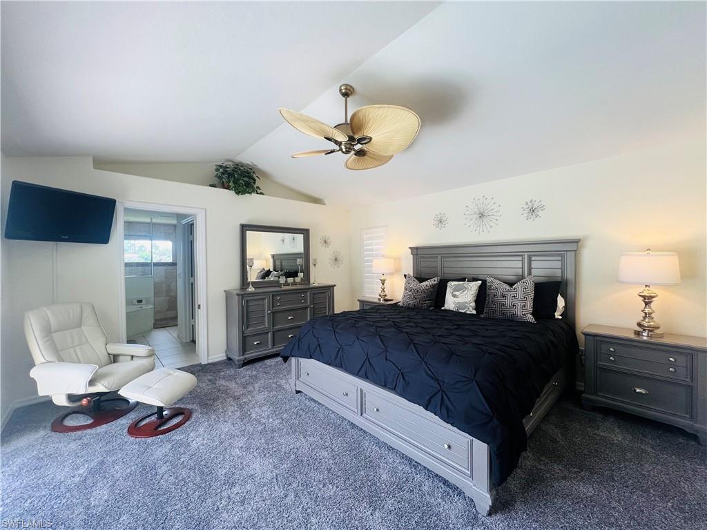 Bedroom featuring ensuite bathroom, with grey carpet, ceiling fan, and lofted ceiling