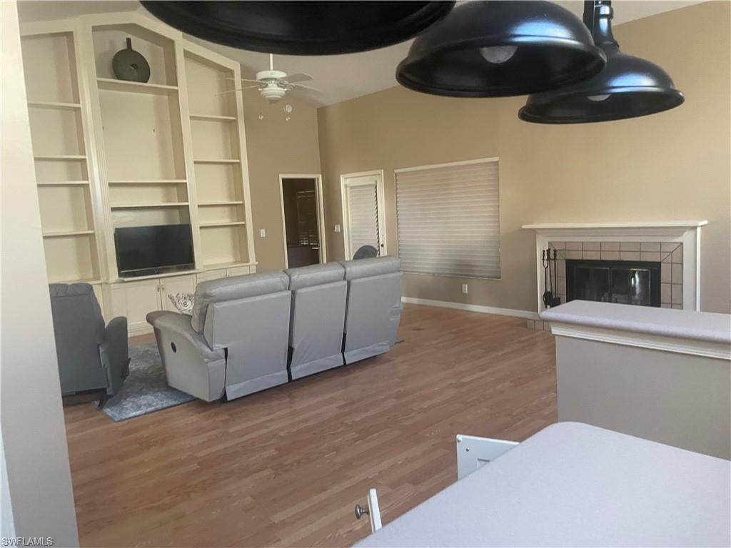 Spacious living area featuring vaulted ceilings, wood-finish flooring, and a built-in entertainment center with shelving