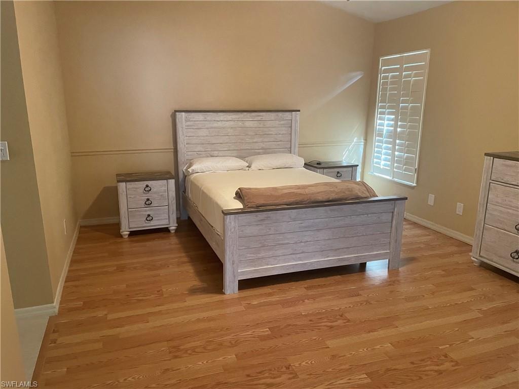 Bedroom featuring wood-finish flooring, neutral wall tones, and white baseboards