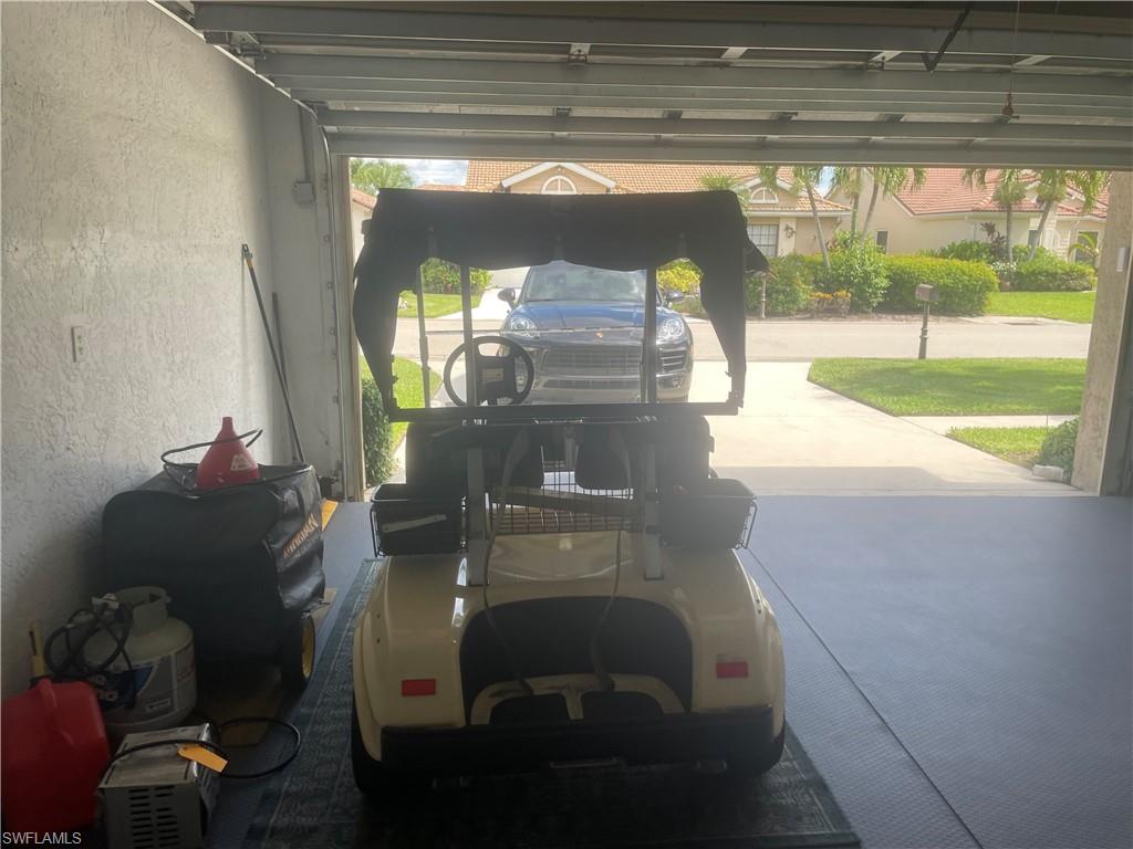 Garage interior featuring a concrete floor with a non-slip mat, painted stucco walls, and a roll-up garage door