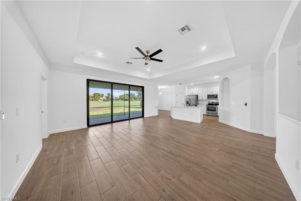 Open concept interior featuring wood-finish flooring and a tray ceiling with recessed lighting