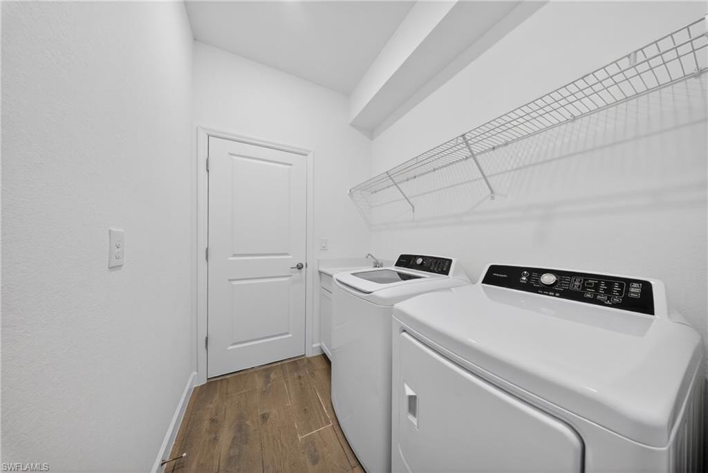Dedicated laundry area featuring wood-finish flooring and white walls