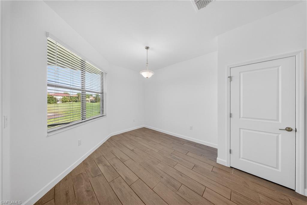 Bright room featuring wood-finish flooring, a large window with horizontal blinds, a ceiling-mounted light fixture, and a two-panel interior door