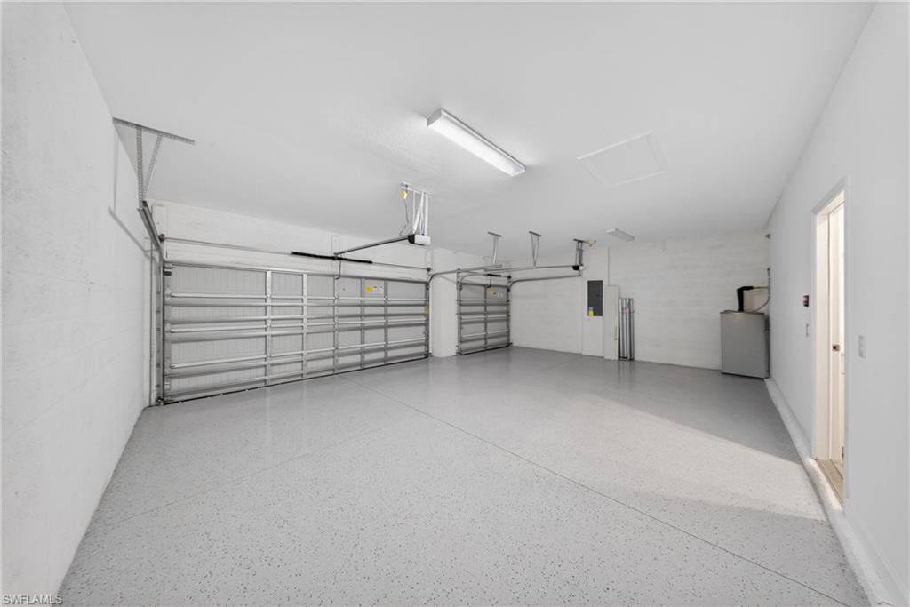 Spacious two-car garage featuring a light gray epoxy flooring, two overhead garage doors, bright overhead lighting, and an access door to the interior