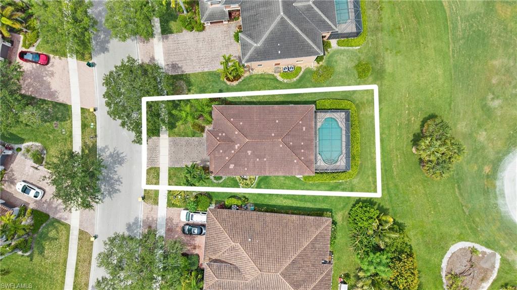 Aerial view showcasing a residential property with a tiled roof and a screened-in pool