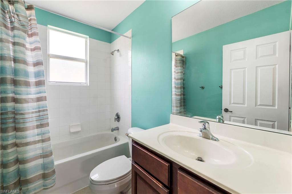Bathroom featuring a built-in vanity with an integrated sink, a large wall-mounted mirror, white ceramic tile shower surround, a full bathtub, and a window for natural light