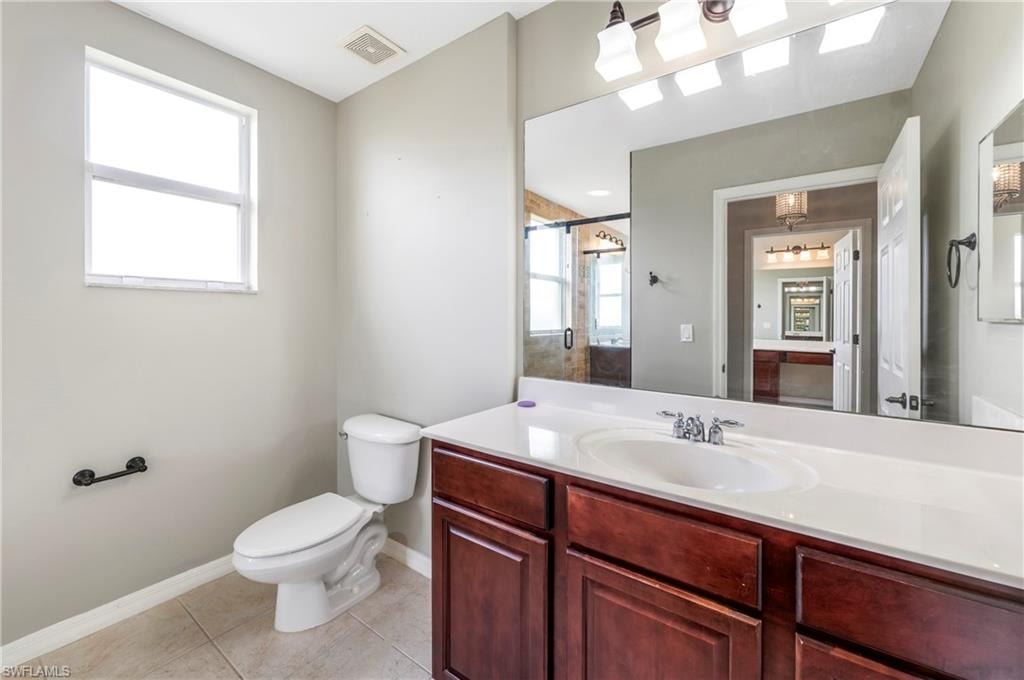 Bathroom featuring a single-sink vanity with white countertop, dark wood-finish cabinetry, and a large wall-mounted mirror