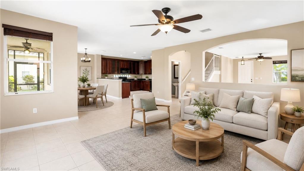 Spacious open-concept living area featuring light-toned tile flooring, recessed lighting, and ceiling fans