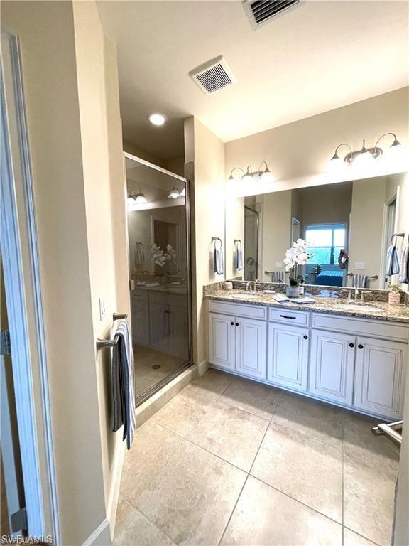 Full bath featuring a shower stall, visible vents, a sink, and double vanity