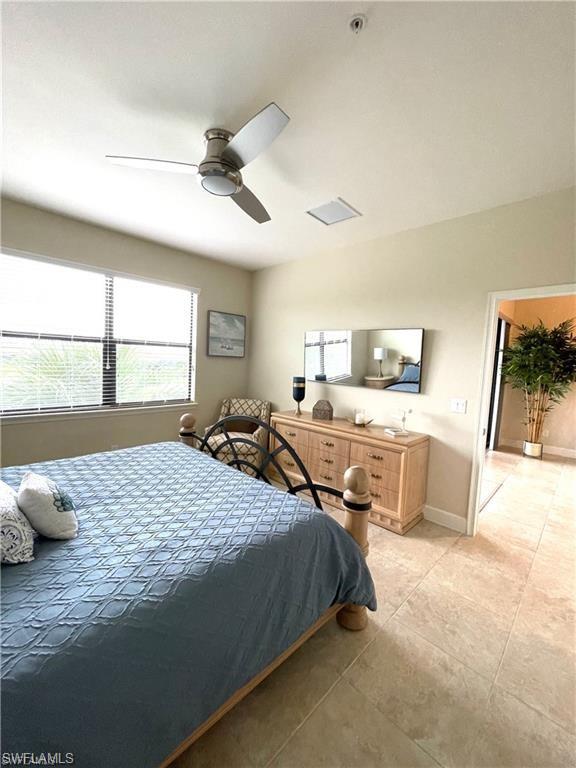 Bedroom with baseboards, ceiling fan, light tile patterned flooring, and lofted ceiling
