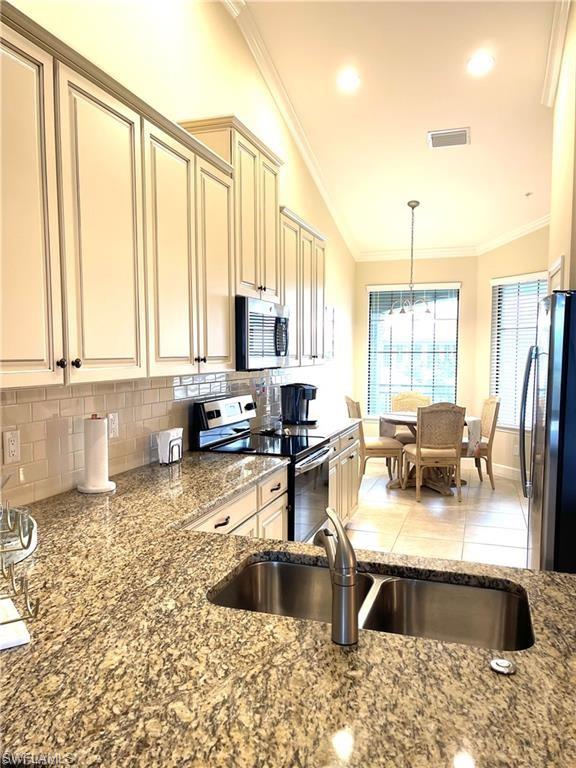 Kitchen with ornamental molding, visible vents, appliances with stainless steel finishes, a sink, and cream cabinets