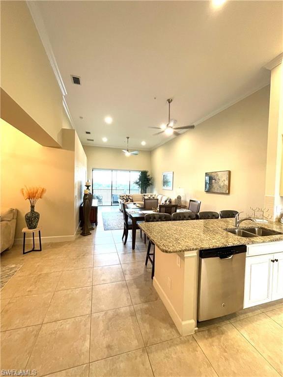 Kitchen featuring dishwasher, a sink, open floor plan, ornamental molding, and a ceiling fan