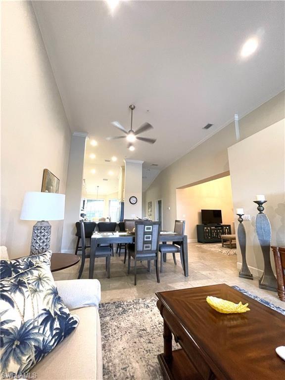 Living area with ornamental molding, visible vents, ceiling fan, and vaulted ceiling