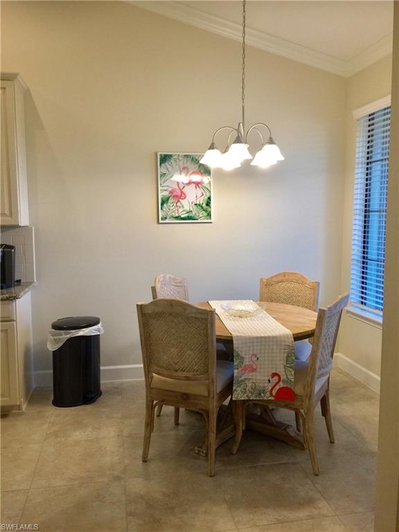 Dining area with light tile patterned floors, a notable chandelier, baseboards, and crown molding