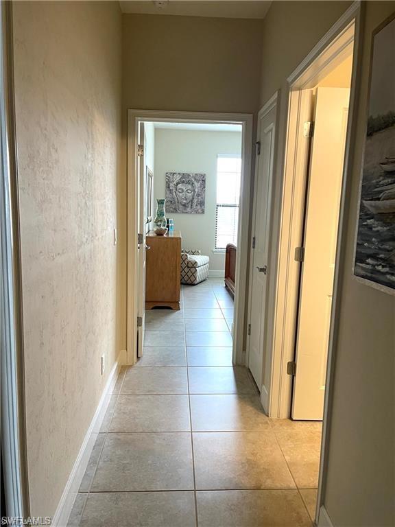 Corridor featuring baseboards and light tile patterned flooring