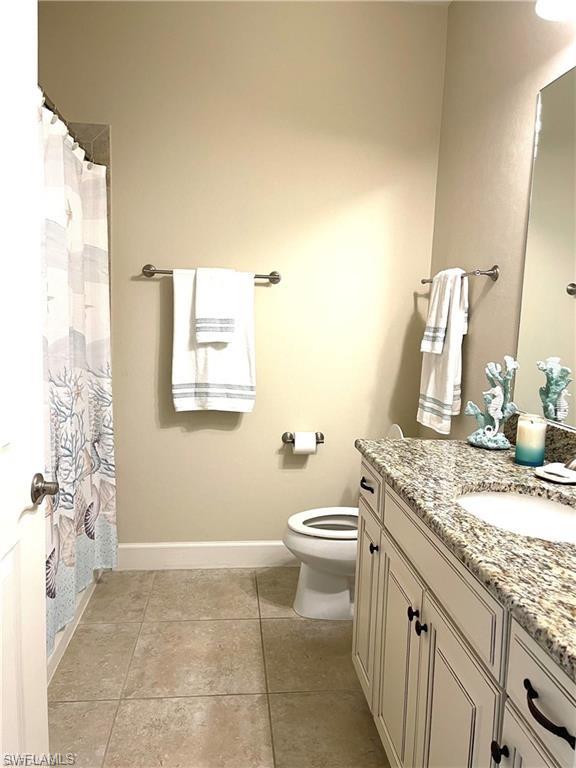 Full bath featuring vanity, toilet, a shower with shower curtain, tile patterned floors, and baseboards