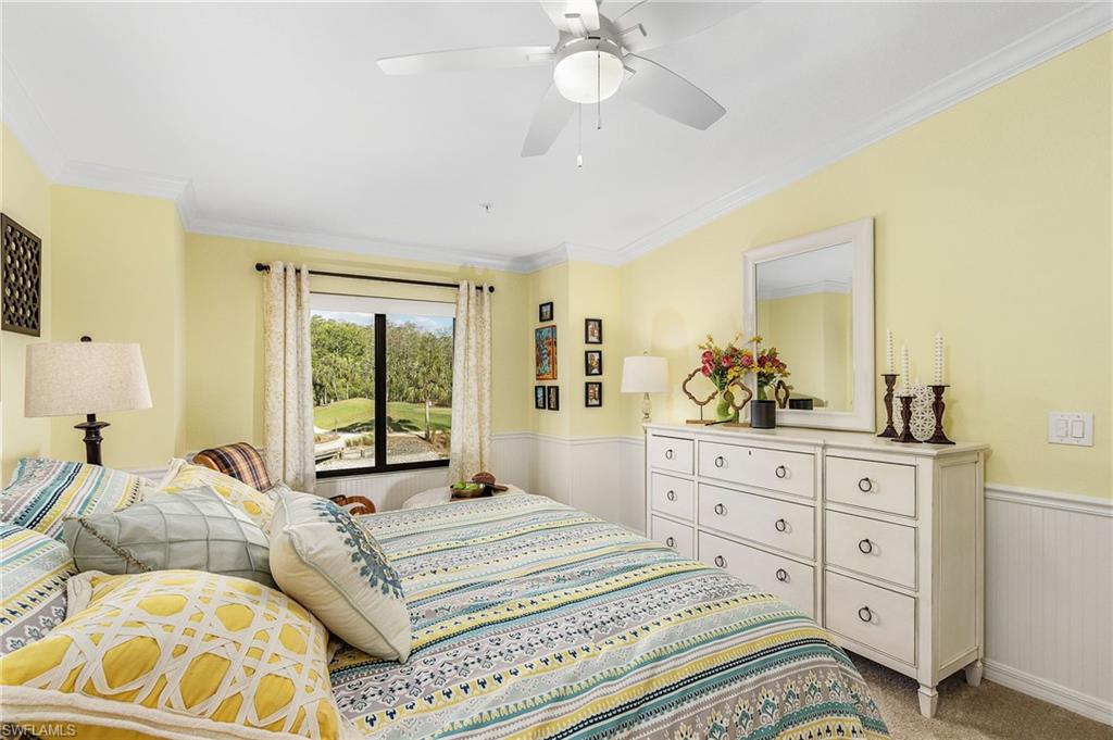 Bedroom with a wainscoted wall, crown molding, ceiling fan, and light carpet
