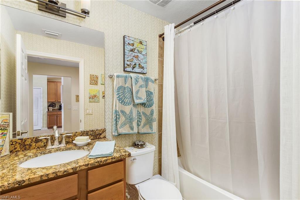 Full bathroom with vanity, shower / bath combo, and wallpapered walls