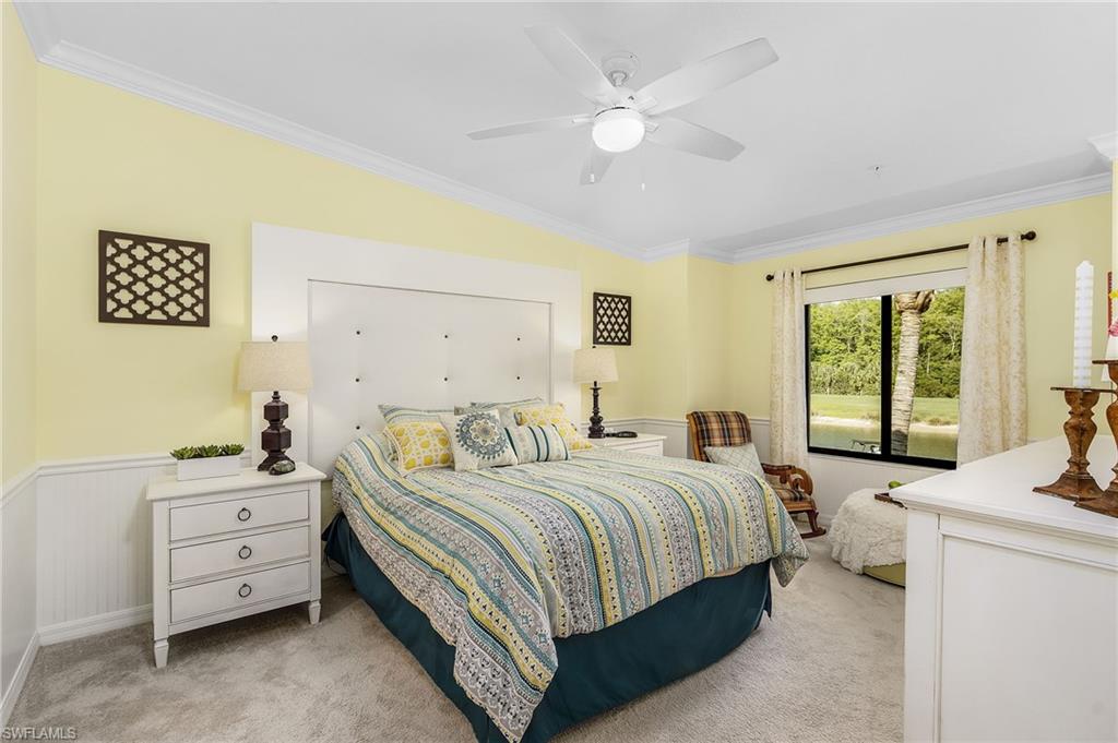 Bedroom with ornamental molding, light carpet, ceiling fan, and a wainscoted wall