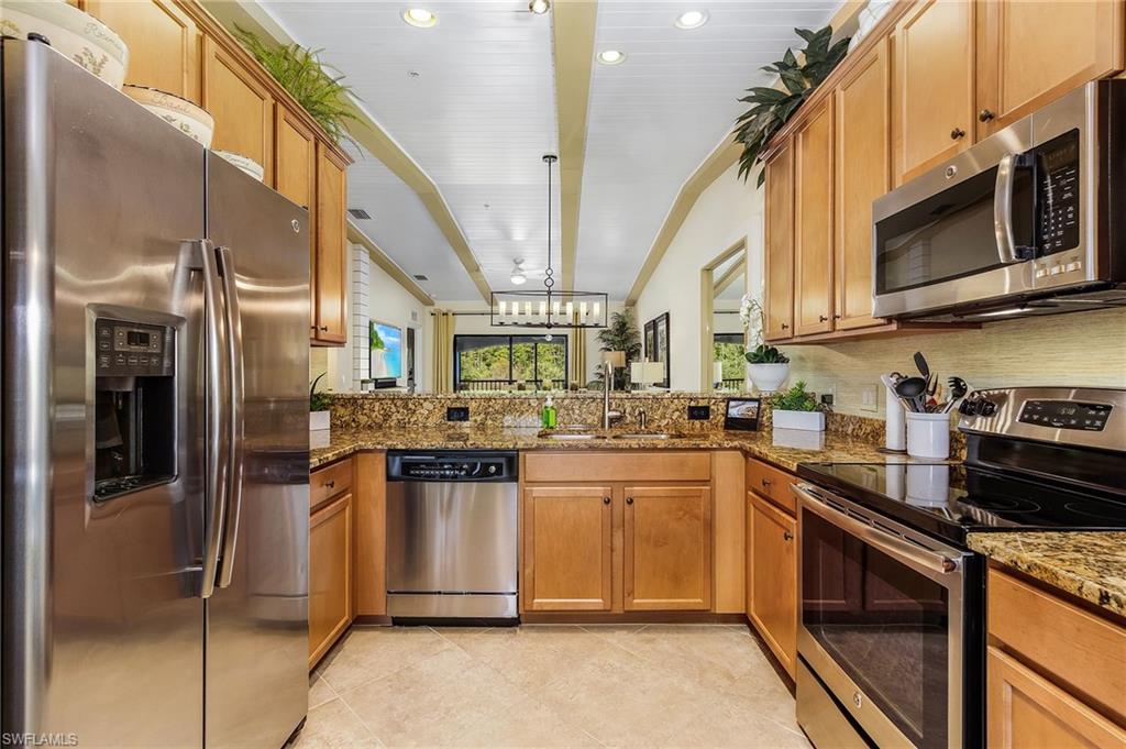 Kitchen featuring appliances with stainless steel finishes, dark stone countertops, brown cabinets, and recessed lighting