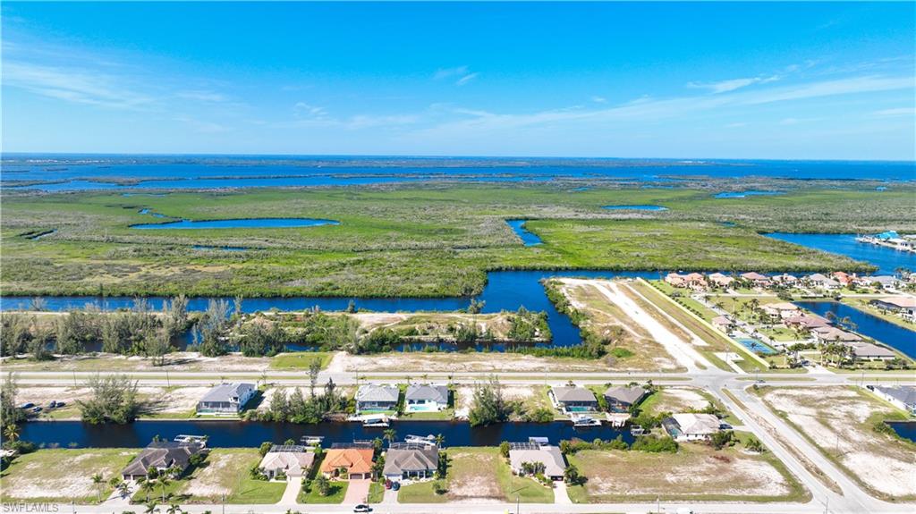 Aerial perspective showcasing a residential area with canal access, undeveloped lots, and a distinct airstrip