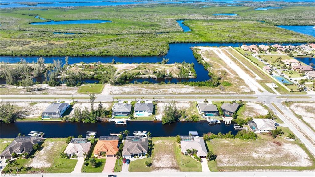 Aerial perspective showcasing multiple homes with individual boat docks along a canal system, bordered by expansive natural wetlands