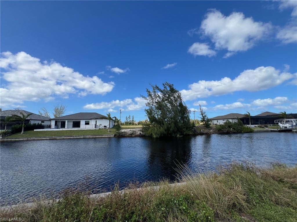 Canal-front property featuring a single-story residence with a dark roof and white exterior