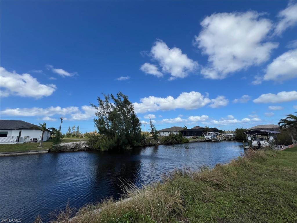 Waterfront canal property with mature trees and a clear blue sky