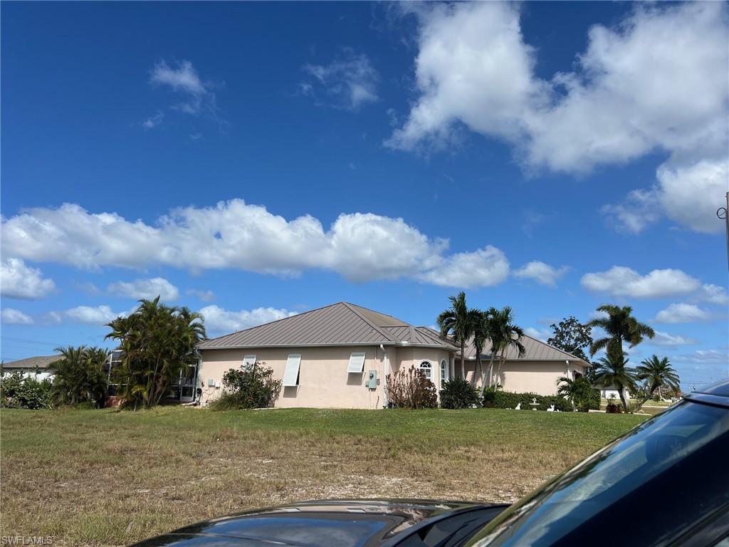 Expansive lot featuring a single-story residence with a light-colored exterior and a gray metal roof