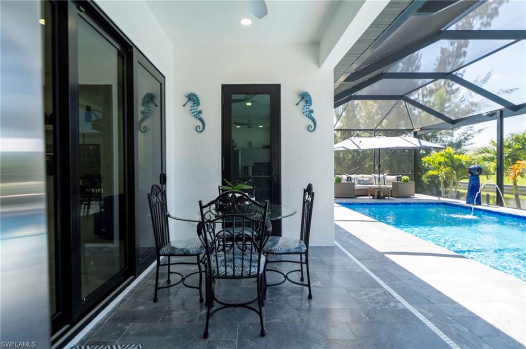 Screened patio with tile flooring, featuring a ceiling fan, sliding glass doors, and direct access to the swimming pool area